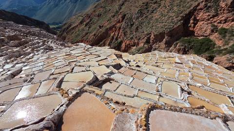       Shimmering stepped salt pans cascading down a mountainside at Maras under bright sun.
  