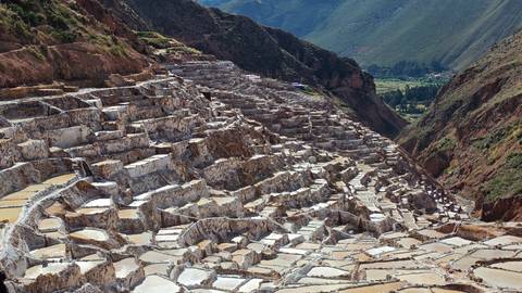       Expansive view down stepped white salt terraces of Maras into green valley below.
  