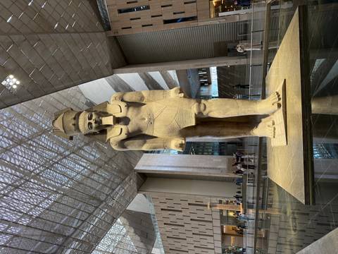       Colossal statue of Ramses II inside the Grand Egyptian Museum with visitors nearby
  