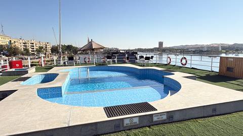       Rooftop swimming pool on a Nile cruise ship with river views and life rings along the deck.
  