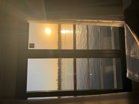      Warm sunset seen through a cabin balcony door reflecting golden light on the Nile waters.
  
