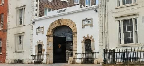       Historic Guinness gate with dates and crest set in a stone archway in Dublin.
  
