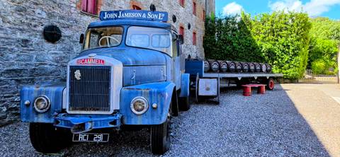       Vintage blue Scammell truck and flatbed with whiskey barrels outside the Jameson distillery.
  