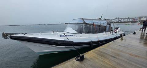       Modern white speedboat named 'Skellig Bounty' moored to a dock on a misty harbour morning.
  
