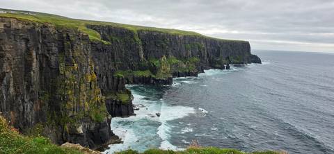      Dramatic Cliffs of Moher plunge into the Atlantic Ocean with waves crashing below
  