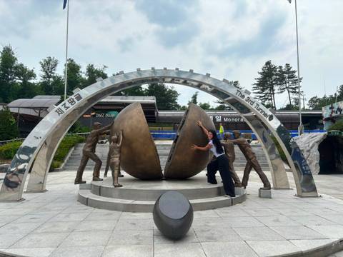       Woman playfully pushes apart two giant bronze doors at the 3rd Tunnel DMZ monument
  