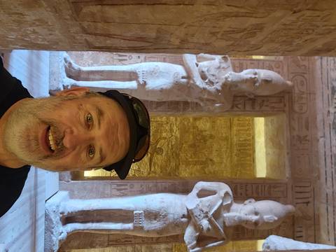       Smiling traveler taking a selfie inside Abu Simbel temple surrounded by colossal statues
  