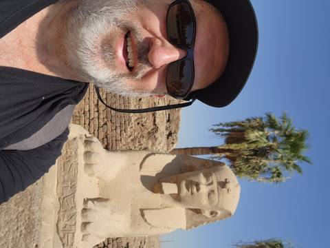       Half-selfie with a small sphinx statue and palm tree at Karnak complex
  