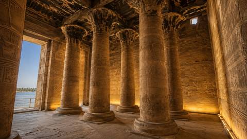       Beautifully lit sandstone columns of Philae Temple overlooking the Nile at golden hour
  