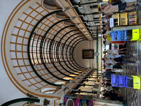       Bustling interior of Ho Chi Minh City’s French colonial Central Post Office with arched glass roof.
  
