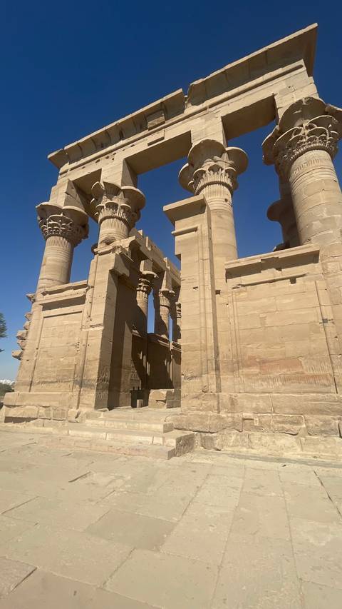       Sunlit sandstone columns and walls of Kom Ombo Temple stand tall against a cloudless sky.
  