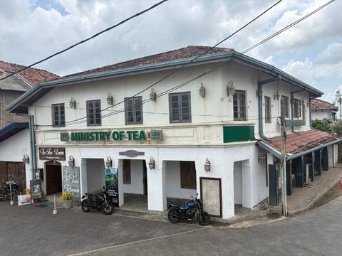       Colonial-era two-storey building labeled 'Ministry of Tea' on a narrow street corner.
  