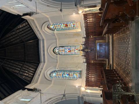       Small chapel interior with dark wooden pews, stained glass windows and a simple altar.
  