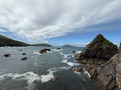       Dramatic rugged Atlantic coastline with jagged rocks and rolling waves under partly cloudy sky
  