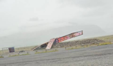       Tilted, blurry image of a graffiti-covered ramp in a foggy, featureless plain
  
