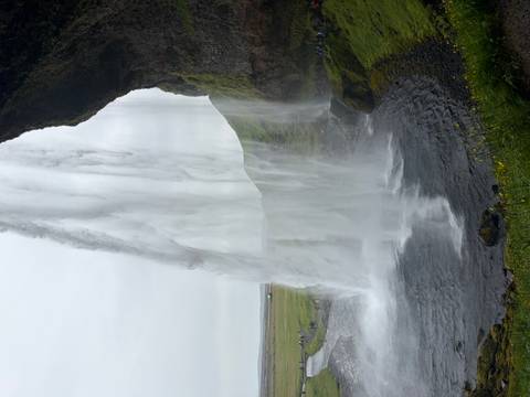       Dramatic side-view from behind Seljalandsfoss waterfall with water plunging into a circular pool
  