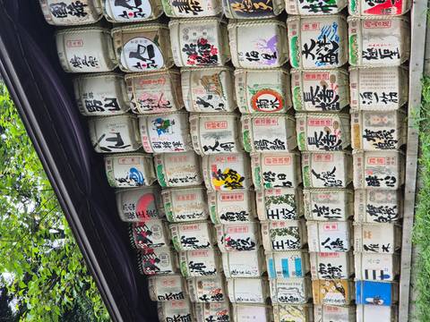       Colorful stacked barrels of sake offerings arranged along a shrine wall.
  