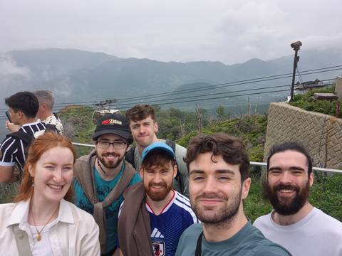       Smiling friends at a foggy mountain lookout platform with cables overhead.
  