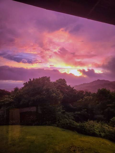       Vibrant pink and purple sunrise over mist-covered forested hills in Monteverde.
  