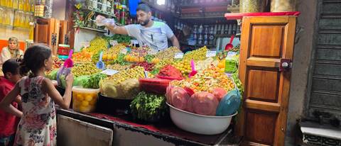       Colourful pickled produce and olives piled high at a vibrant Moroccan market stall lit warmly at night.
  