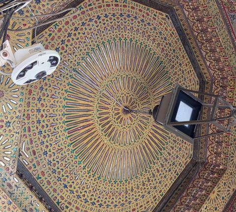       Highly detailed mosaic ceiling with geometric patterns, lantern and modern security camera.
  