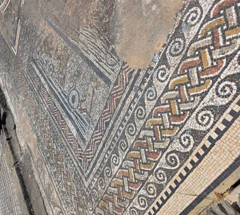       Detailed ancient Roman mosaic floor with colorful geometric patterns at an archaeological site
  
