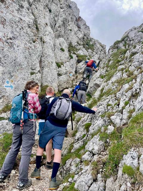       Close view of trekkers negotiating rocky mountain gully on marked trail
  