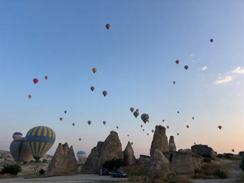       Dozens of colorful hot-air balloons rise over Cappadocia’s rock spires at dawn beneath a pastel sky.
  