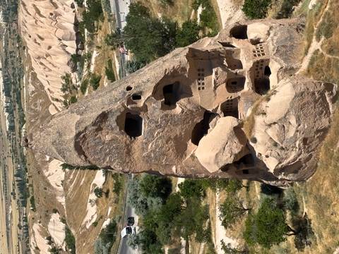       A towering tuff cone riddled with cave dwellings rises above the Cappadocian landscape.
  