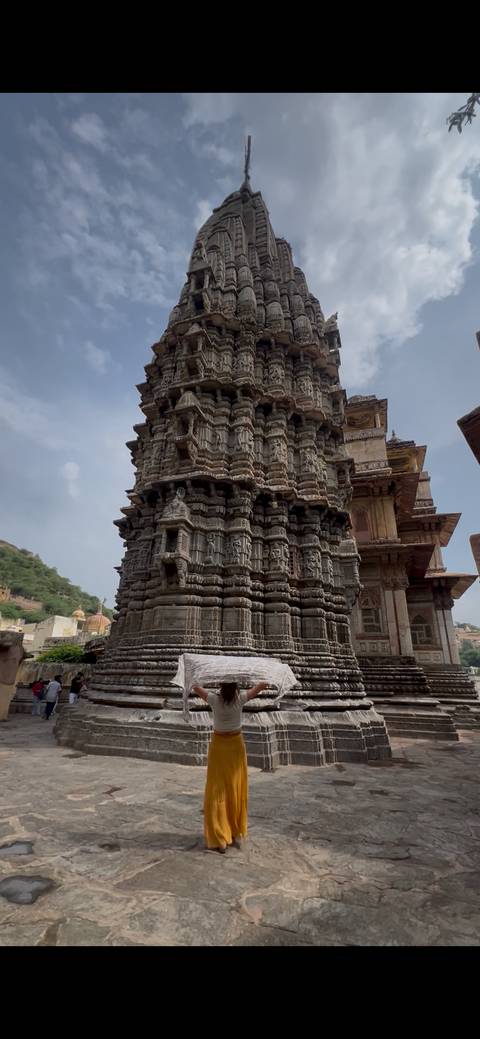       Close view of intricately carved stone temple tower with layered sculptural details.
  