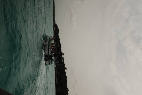       Motorboat carrying passengers speeds across turquoise water under a hazy sky.
  