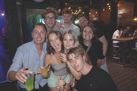       Group of friends enjoy drinks at lively outdoor bar at night
  