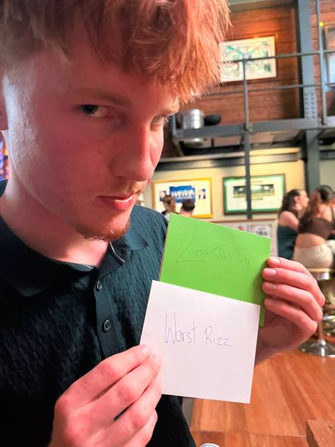       Man holds handwritten green note in casual bar setting
  