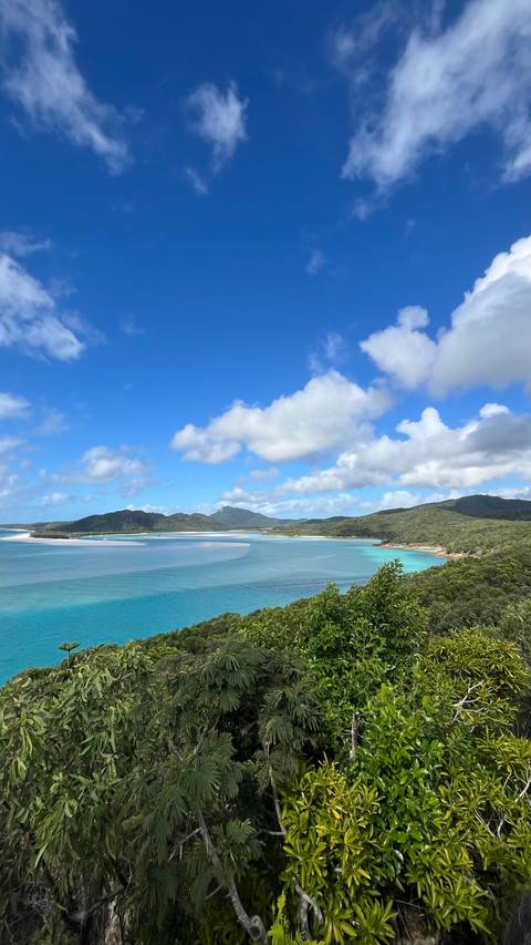       Expansive view of turquoise inlets, white sands, and forested islands under scattered clouds
  