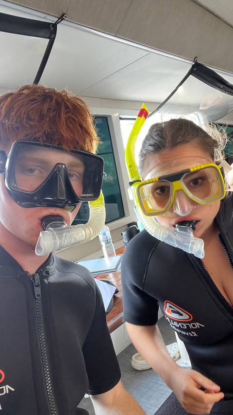       Two snorkellers wearing masks and snorkels take a close selfie before entering the water
  