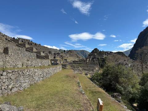       Panoramic view of Machu Picchu's stone terraces and citadel ruins under a clear blue sky.
  
