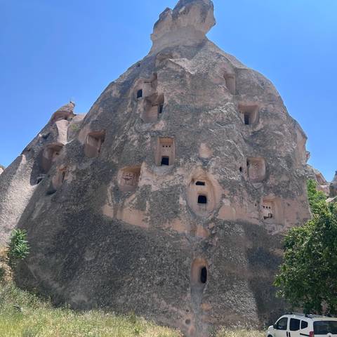       Steep fairy-chimney cliff riddled with ancient cave dwellings and small window openings.
  