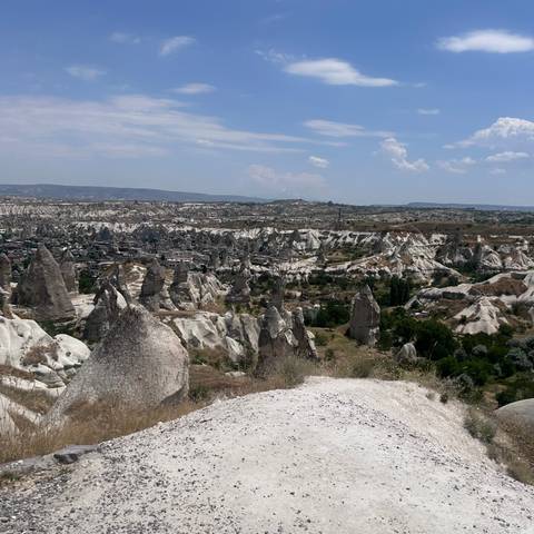       Wide panorama of white-tipped fairy chimneys and villages scattered across Cappadocia’s rugged valley.
  