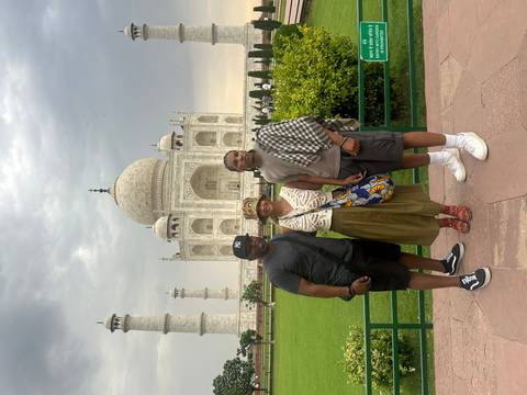      Friends pose for a snapshot with the Taj Mahal’s iconic dome and minarets rising behind them.
  