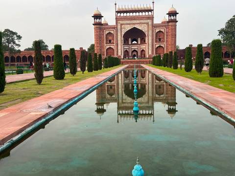       Grand Mughal gateway and reflecting pool perfectly mirror the intricate red sandstone architecture.
  
