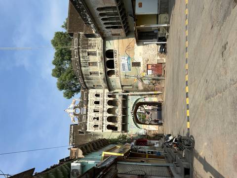       Historic town gate archway with weathered murals and pedestrians in a small Indian town.
  