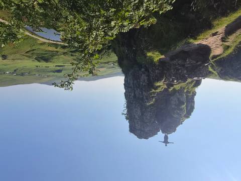       Adventurer stands with arms outstretched atop a rocky pinnacle overlooking rolling green hills on the Isle of Skye.
  