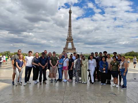       Large tour group posing in front of the Eiffel Tower on a partly cloudy day
  