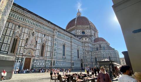       Majestic marble façade and iconic red-tiled dome of Florence’s Duomo with bustling square full of visitors.
  