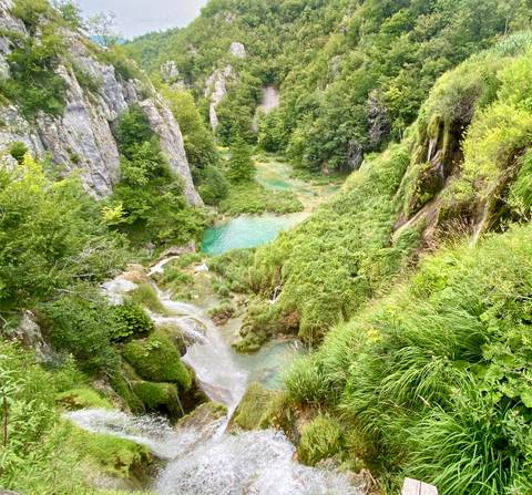       Verdant limestone canyon with cascading turquoise pools and waterfalls in Plitvice Lakes National Park.
  