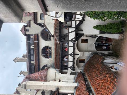       Interior balconies and terracotta roofs of Bran Castle bustling with tourists on a rainy day.
  