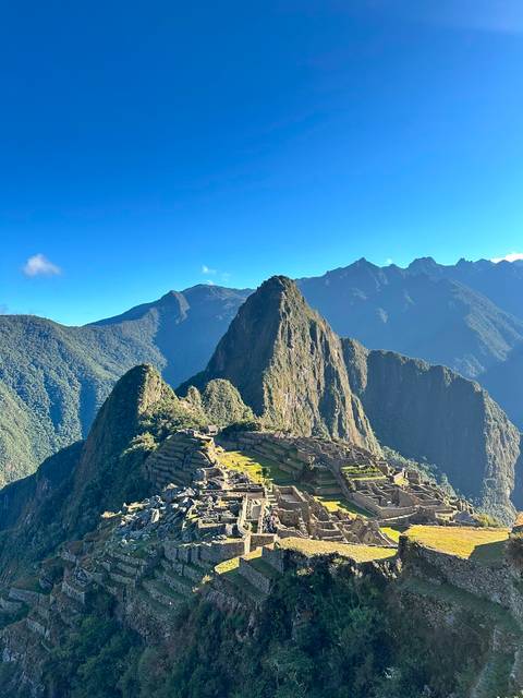       Iconic Machu Picchu terraces and Huayna Picchu peak rise majestically above lush cloud forest.
  