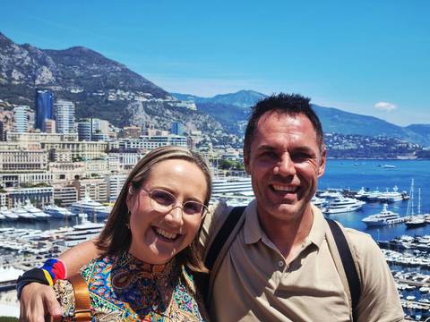       Couple with Monaco’s yacht-filled harbour and rugged hillsides in the background
  