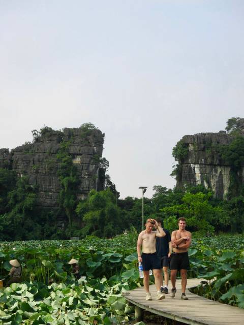       Limestone karst towers rise behind two smiling travellers posing in lush green scenery
  