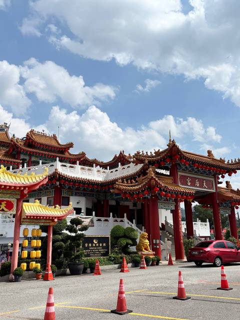       Ornate red-and-gold Thean Hou Temple under bright blue sky with fluffy clouds
  